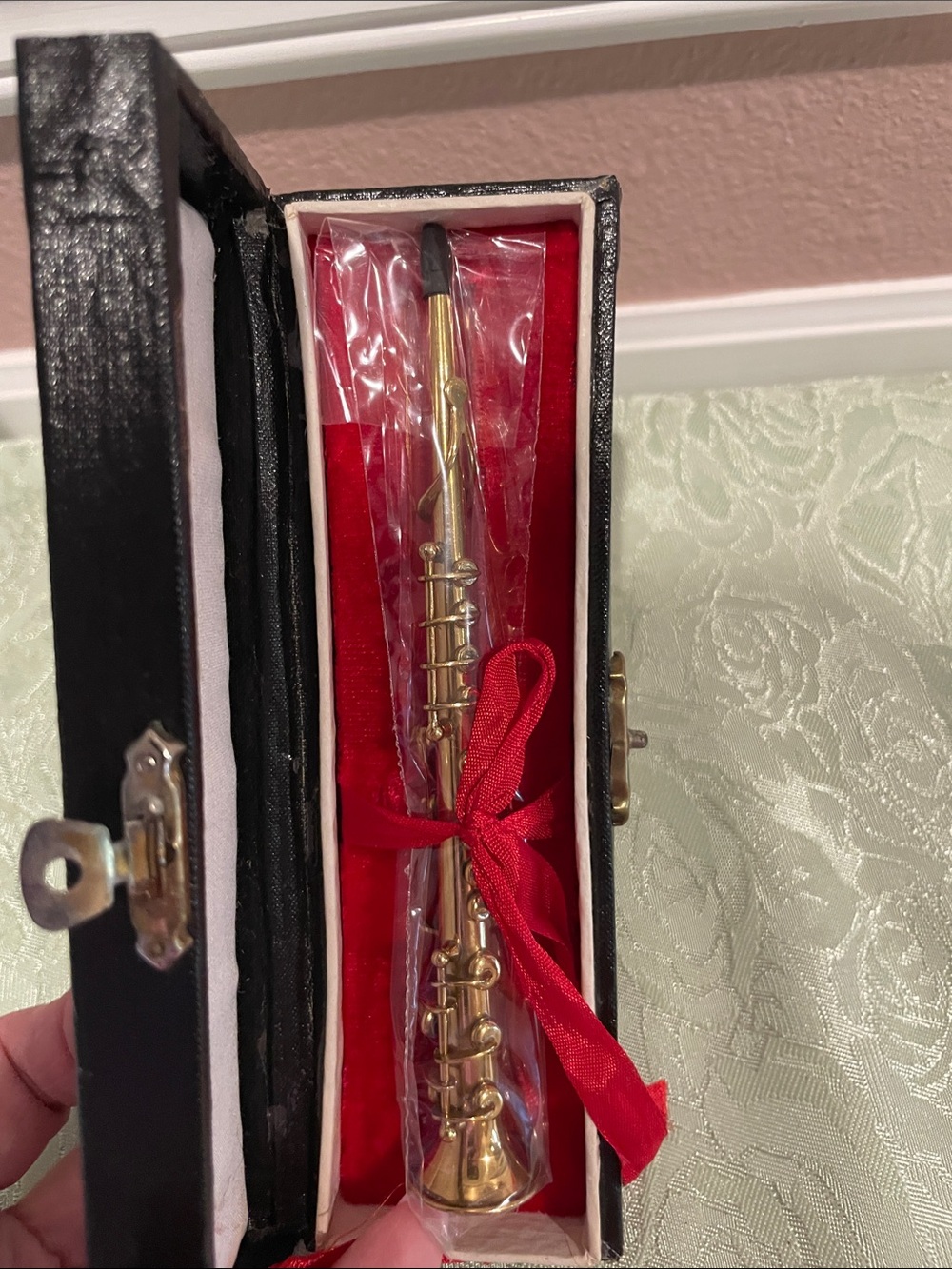 Miniature Brass Colored Clarinet in a red velvet case.